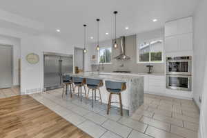 Kitchen featuring light stone countertops, light tile patterned floors, stainless steel appliances, a kitchen breakfast bar, and an island with sink