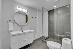 Bathroom with vanity, a walk in shower, and dark tile patterned floors