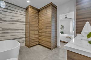 Ensuite bathroom featuring a freestanding bath, vanity, light tile patterned flooring, tile walls, and recessed lighting