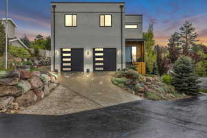 Modern home with stucco siding, an attached garage, concrete driveway, and stone siding