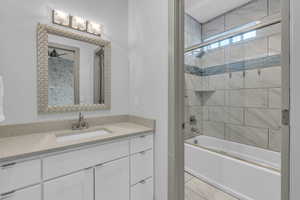 Bathroom with vanity and bath / shower combo with glass door