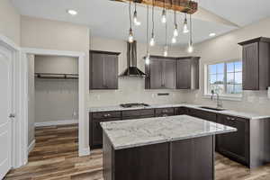 Kitchen featuring a center island, dark wood finish cabinets, decorative light fixtures, and dark wood-style floors