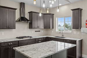 Kitchen featuring light stone countertops, dark wood finish cabinets, and a kitchen island