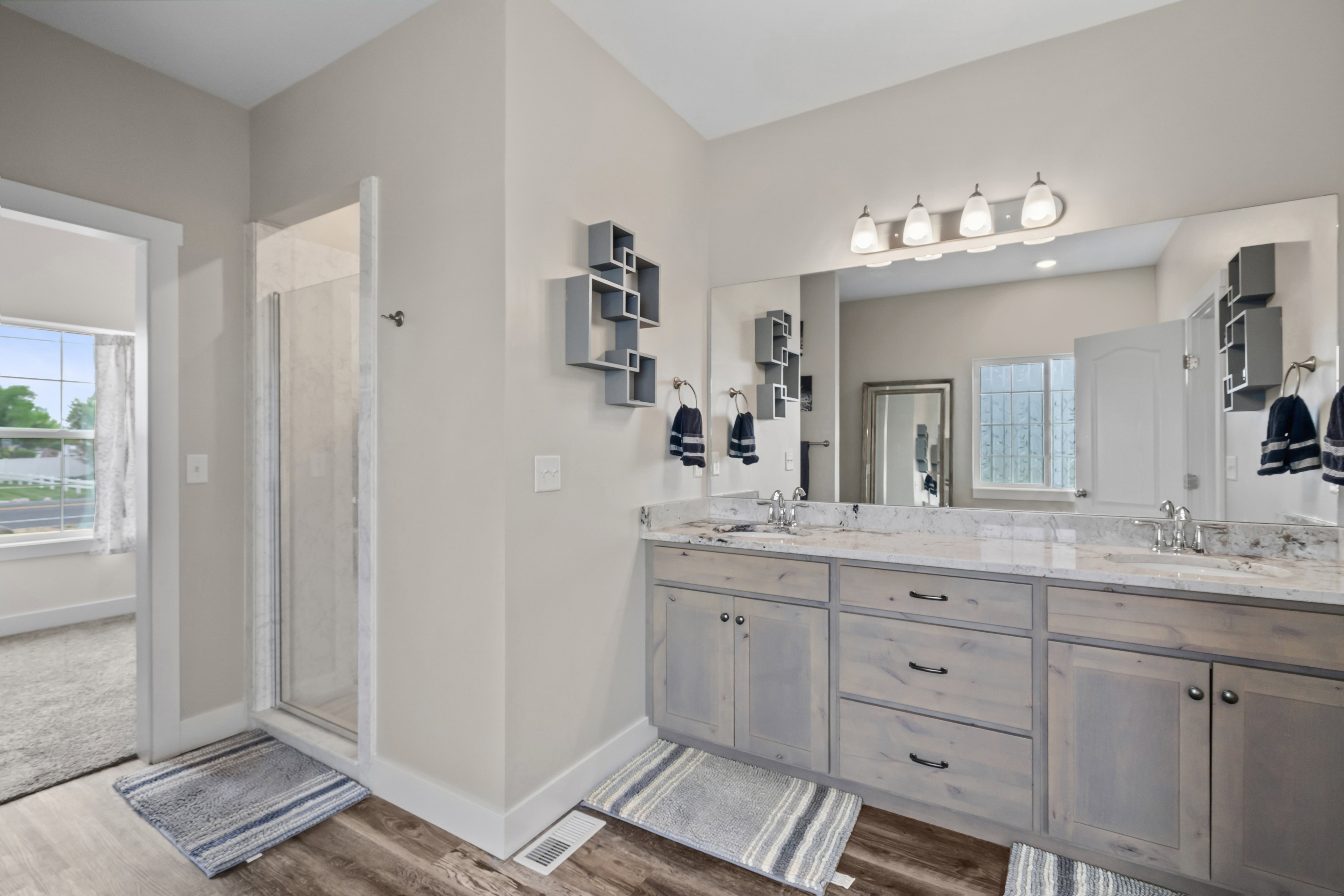 Full bath with double vanity, a shower stall, and dark wood finished floors