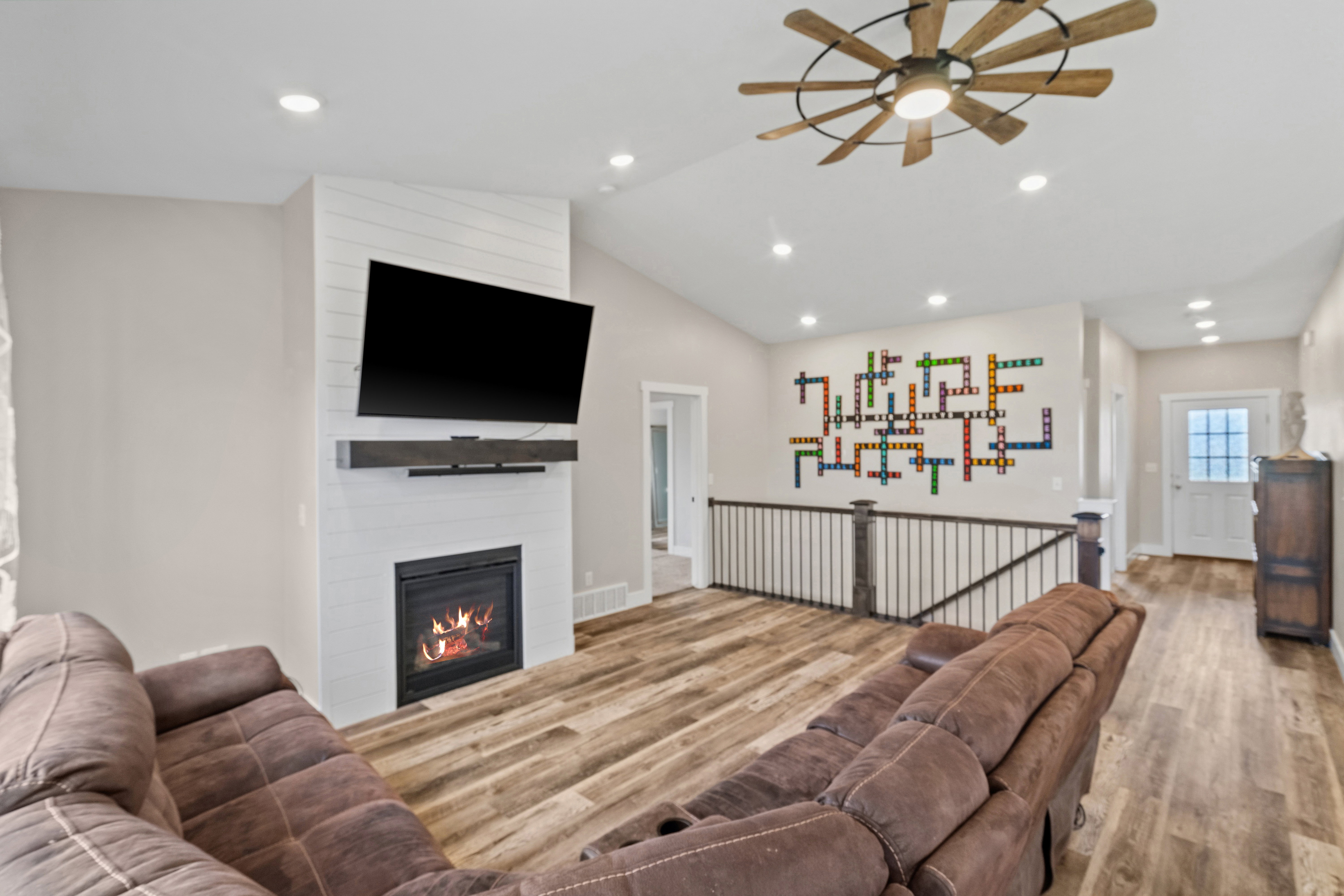 Living area featuring ceiling fan, lofted ceiling, wood finished floors, a fireplace, and recessed lighting