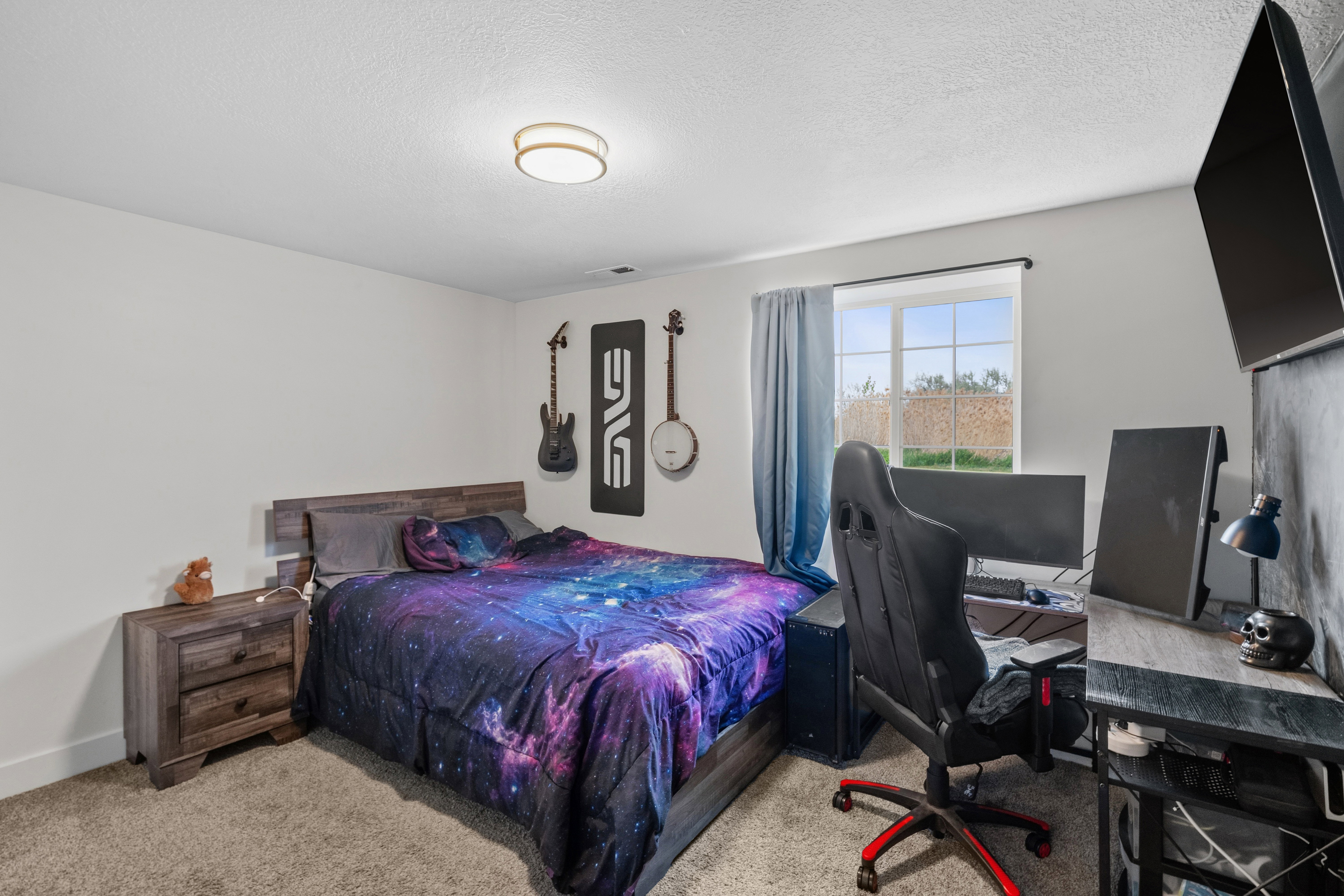 Bedroom with a desk, light colored carpet, and a textured ceiling