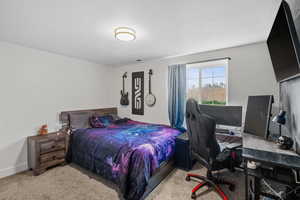 Bedroom with a desk, light colored carpet, and a textured ceiling