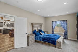 Bedroom featuring light carpet, vaulted ceiling, and recessed lighting