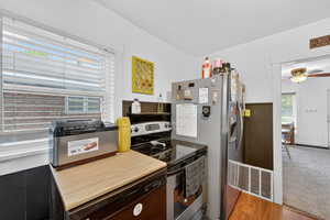 Kitchen with stainless steel appliances, ceiling fan, light wood-style floors, and wainscoting