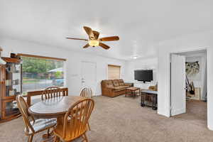 Dining area with light carpet and a ceiling fan