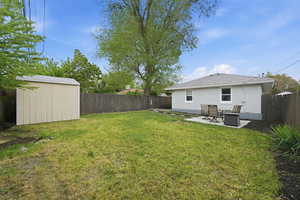 Back of property featuring a fenced backyard, a patio area, and a storage shed