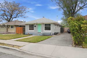 Bungalow-style home with a shingled roof, brick siding, driveway, and an outbuilding