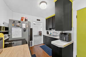 Kitchen with light countertops, dark cabinetry, light wood-style floors, stainless steel appliances, and a textured ceiling