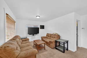 Living area featuring light colored carpet and baseboards