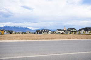 View of asphalt street with curbs, a residential view, and a mountain view