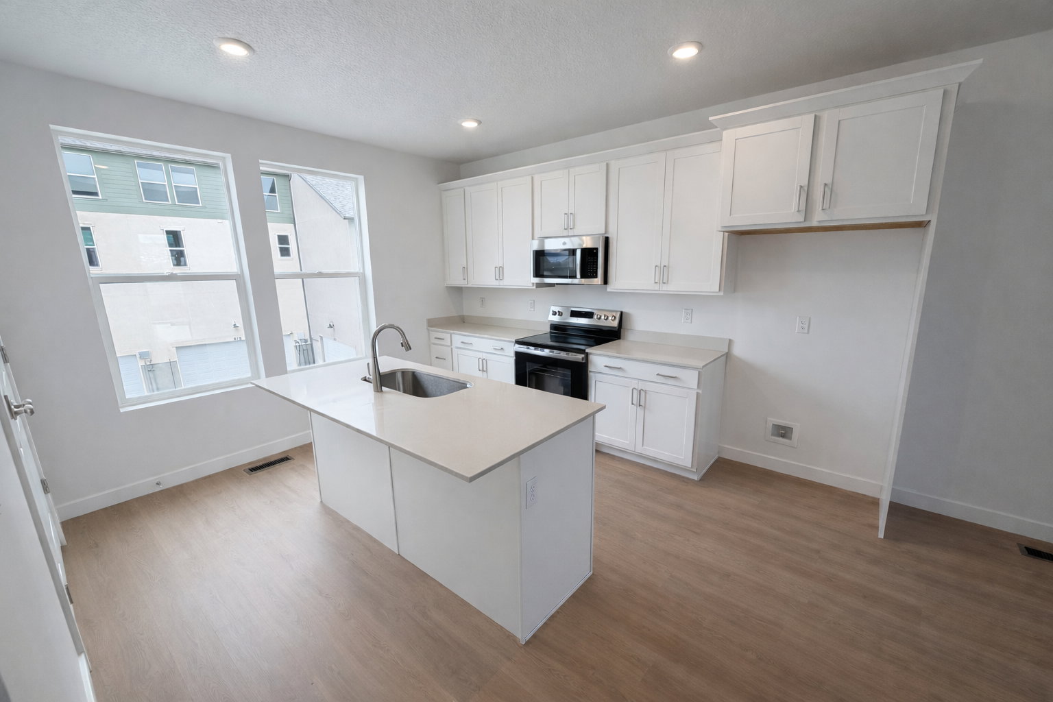 Kitchen featuring white cabinetry, stainless steel appliances, light wood finished floors, a center island with sink, and recessed lighting