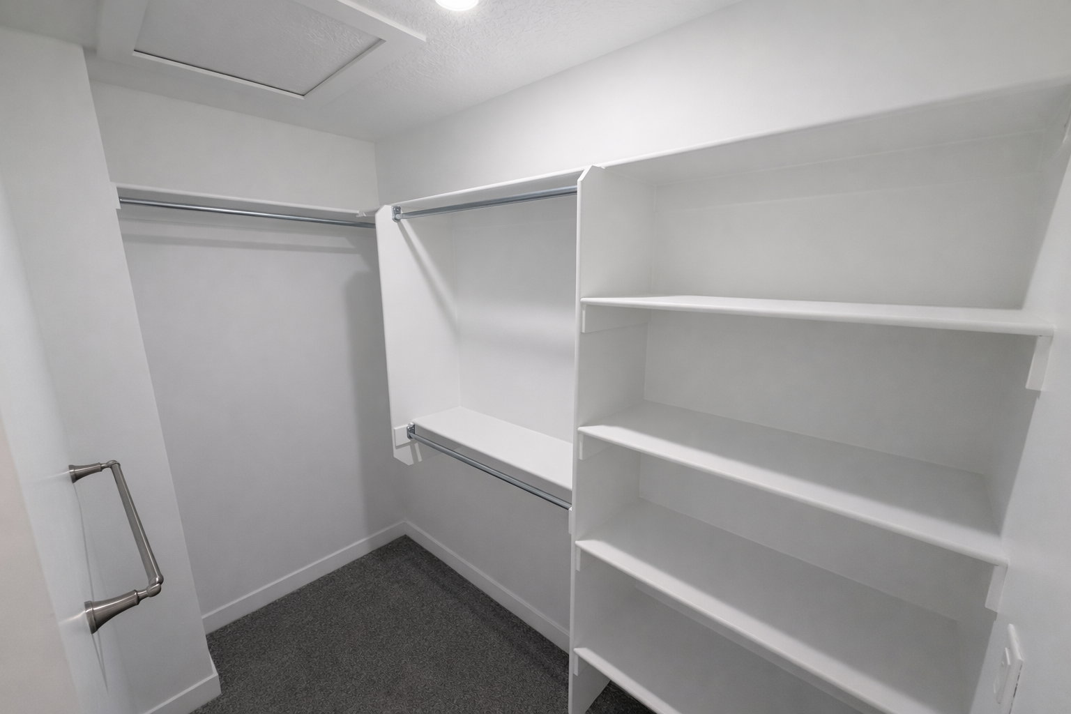 Walk in closet with attic access and dark colored carpet