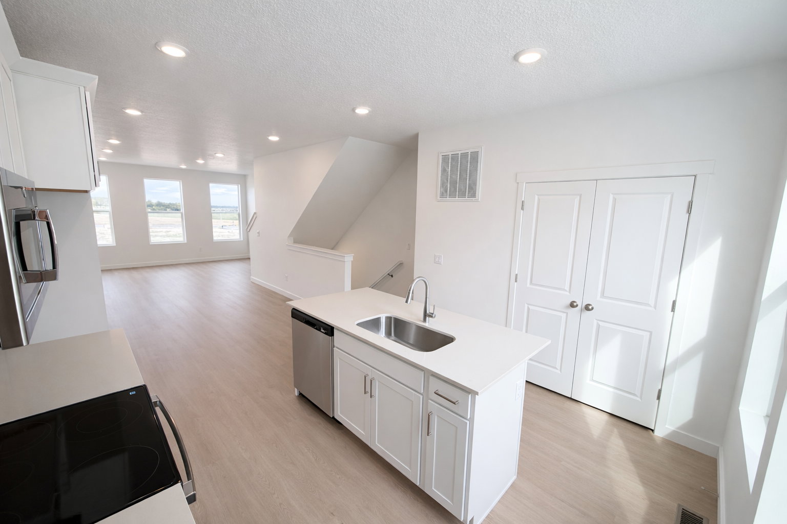 Kitchen featuring white cabinets, open floor plan, a kitchen island with sink, light wood-style flooring, and recessed lighting