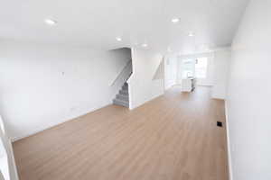 Unfurnished room with light wood finished floors, recessed lighting, and a textured ceiling