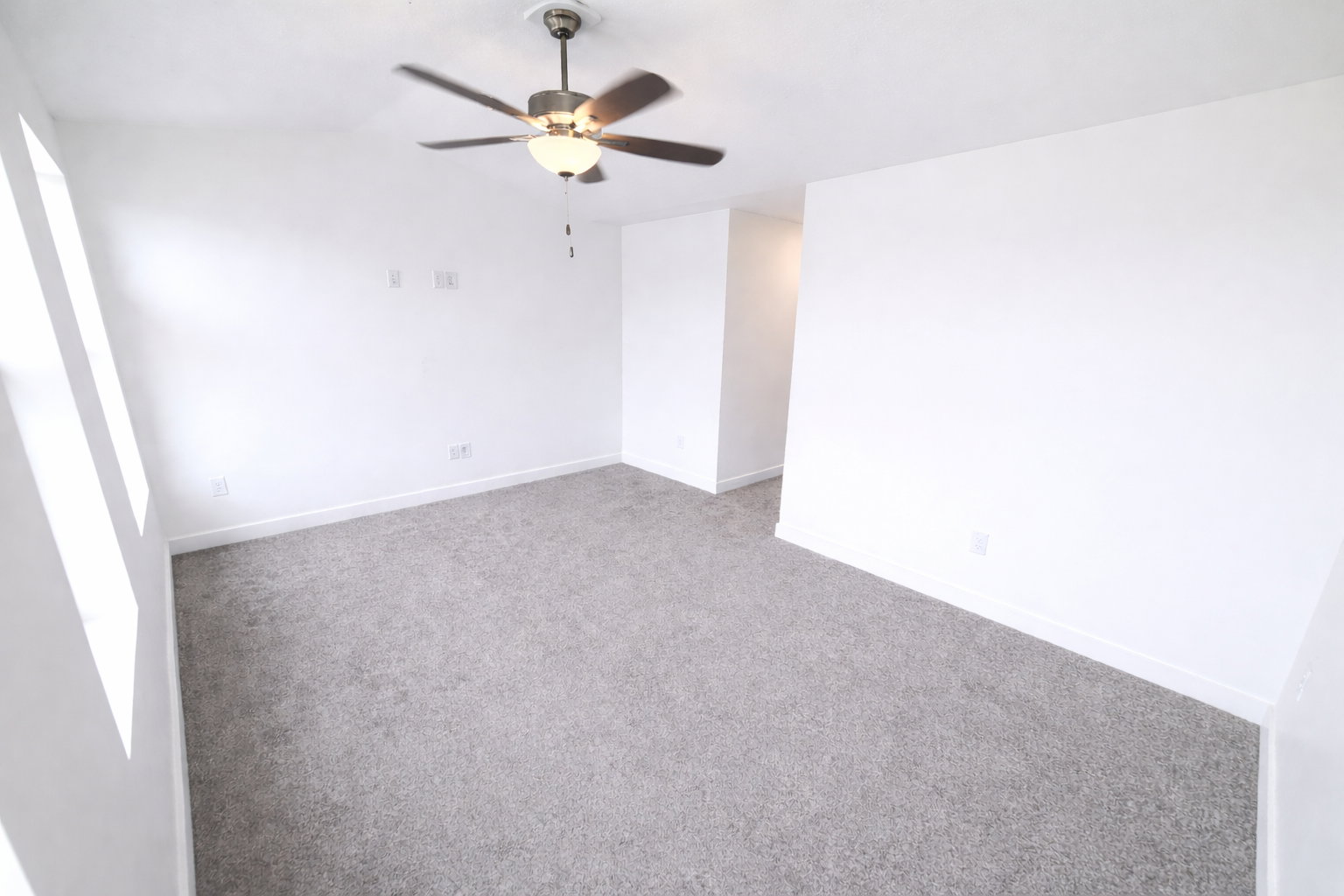 Empty room with carpet, a ceiling fan, and vaulted ceiling