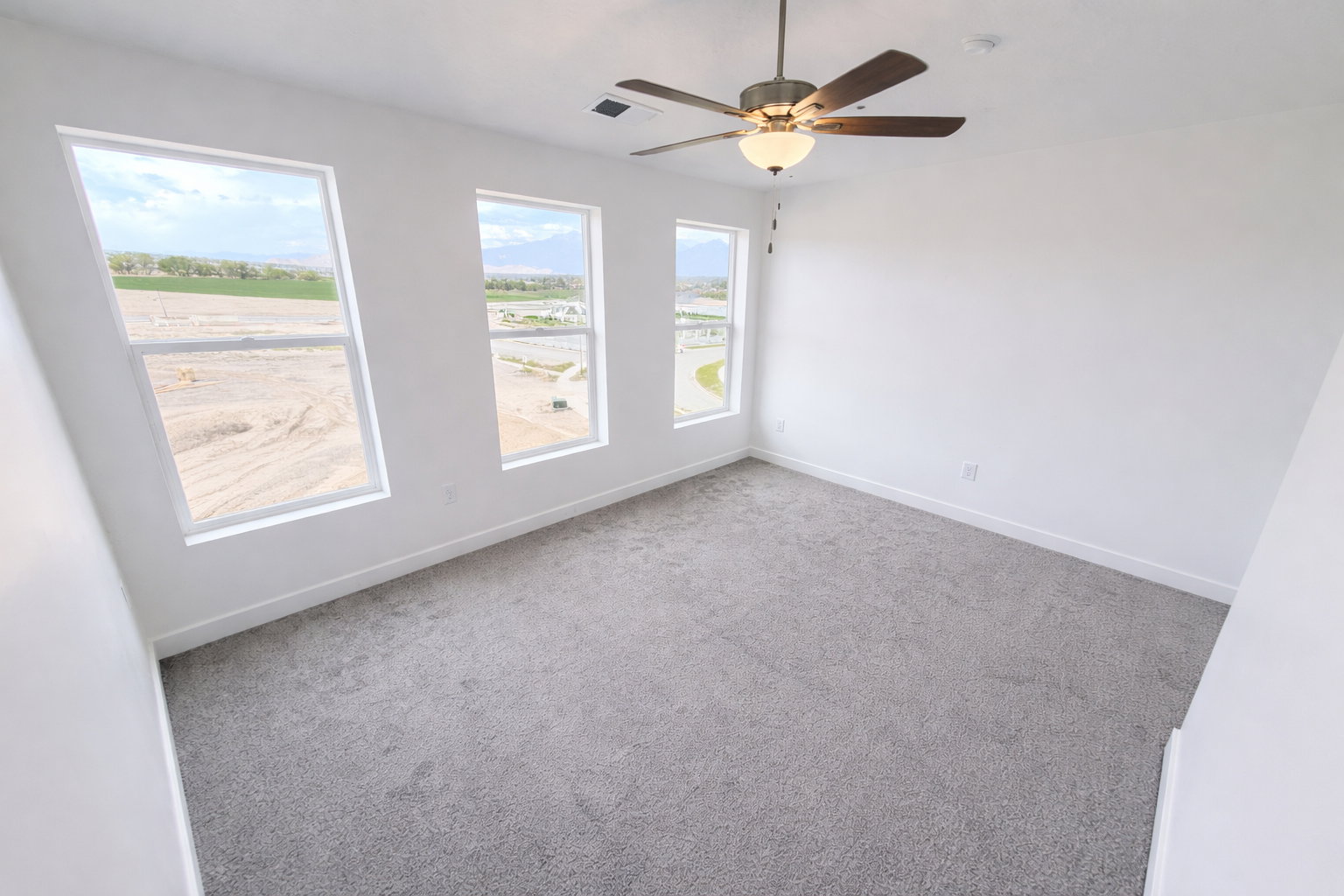 Empty room featuring carpet and a ceiling fan