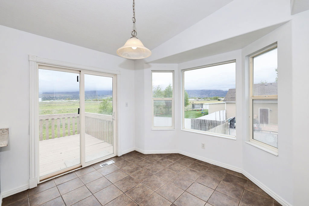 Unfurnished dining area with vaulted ceiling, plenty of natural light, and dark tile patterned floors