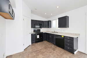 Kitchen featuring black appliances, dark cabinets, vaulted ceiling, light countertops, and recessed lighting
