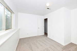 Spare room featuring light colored carpet and baseboards