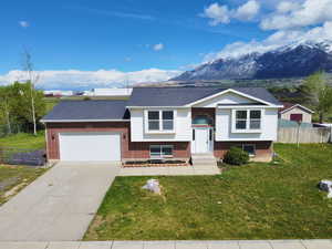 Raised ranch with a garage, concrete driveway, a mountain view, and brick siding