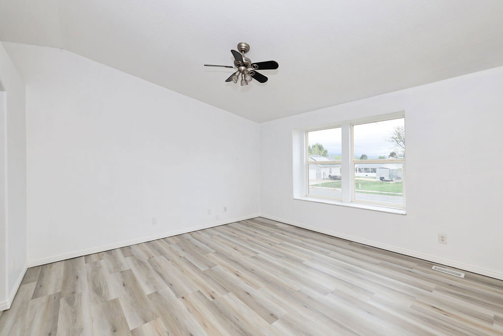 Unfurnished room featuring light wood-style floors, a ceiling fan, and lofted ceiling