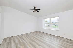 Unfurnished room featuring light wood-style floors, a ceiling fan, and lofted ceiling