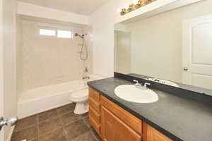 Full bathroom with vanity, shower / bathtub combination, and dark tile patterned flooring