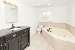 Full bathroom featuring a whirlpool tub, light tile patterned floors, and vanity