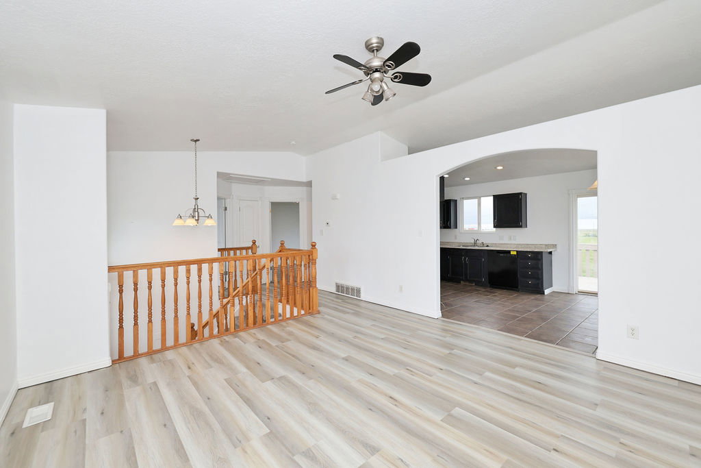 Spare room featuring ceiling fan, light wood-style floors, vaulted ceiling, and suspended lighting