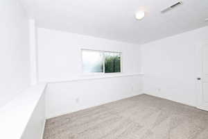 Carpeted spare room featuring baseboards