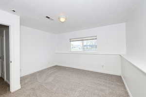 Unfurnished room with light colored carpet and a textured ceiling