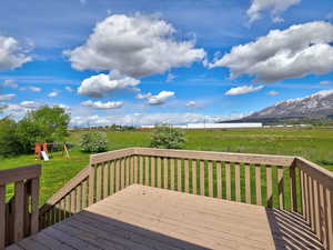 Wooden deck with a lawn, a view of rural / pastoral area, and a playground