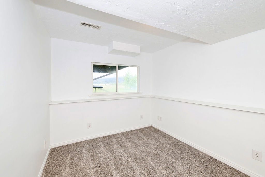 Empty room featuring dark colored carpet and a textured ceiling