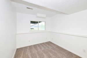 Empty room featuring dark colored carpet and a textured ceiling