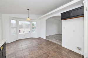 Unfurnished dining area with arched walkways and dark tile patterned floors