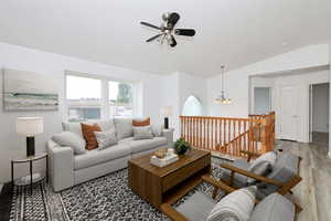 Living room featuring ceiling fan, vaulted ceiling, suspended lighting, and wood finished floors
