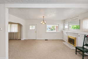 Unfurnished living room with light carpet, a fireplace, and a chandelier