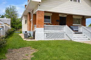 Entrance to property featuring brick siding, a chimney, and covered porch