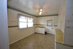 Kitchen with ceiling fan, white dishwasher, dark floors, and white cabinetry