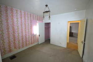 Unfurnished bedroom with wallpapered walls, carpet flooring, and a closet