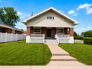 Bungalow-style house with covered porch, a front yard, and brick siding