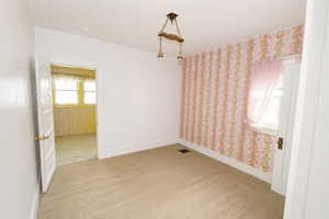 Empty room featuring light carpet and wallpapered walls