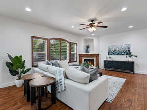 Living area with a ceiling fan, a glass covered fireplace, dark wood-style floors, and recessed lighting