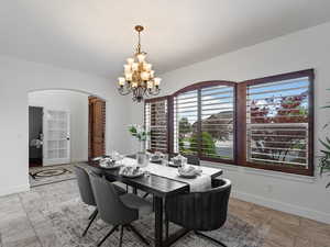 Dining space featuring arched walkways and a chandelier