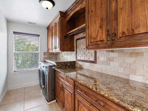 Laundry area with cabinet space, a textured ceiling, light tile patterned floors, and washer and dryer